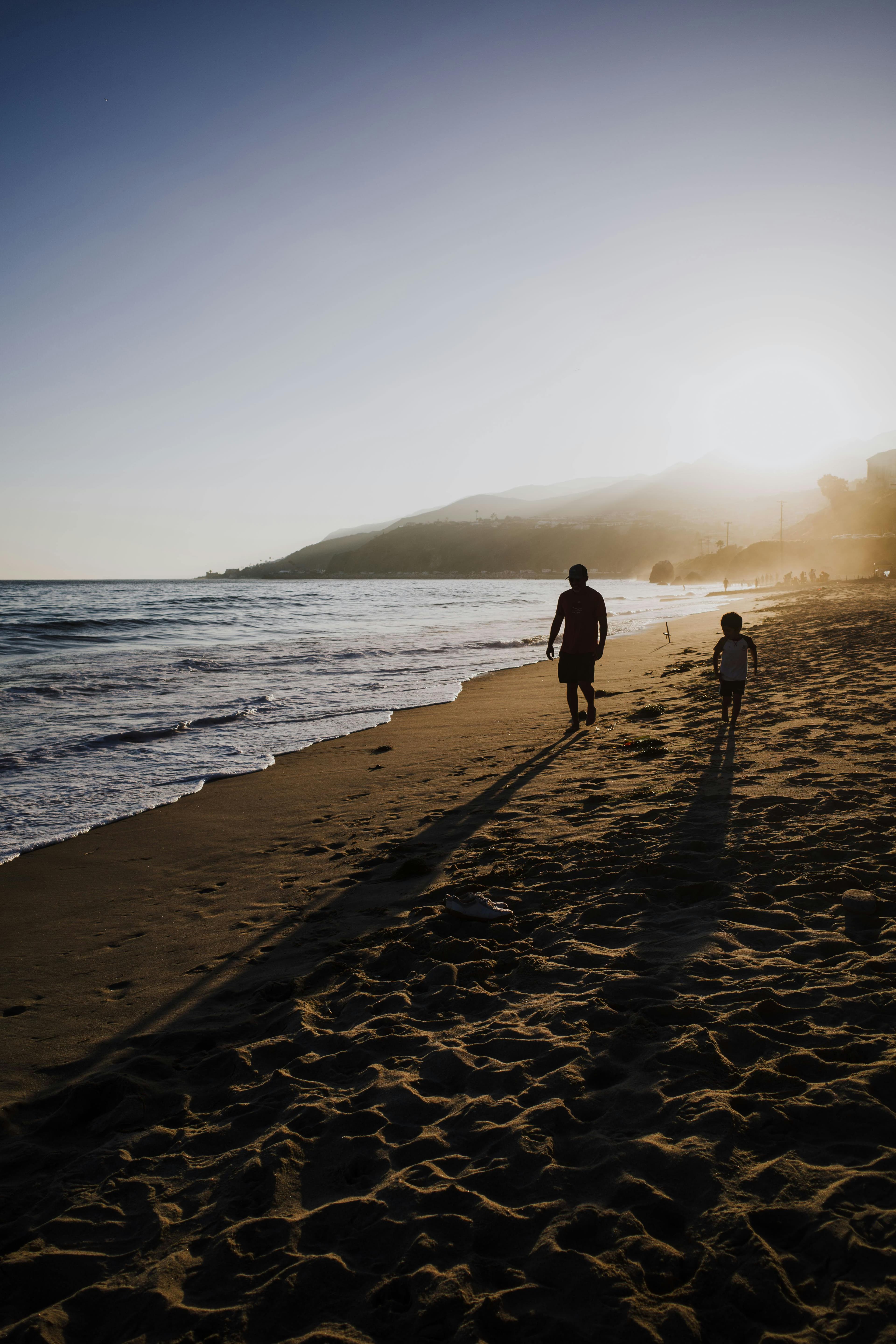 Padre e hijo caminando en una playa del Pacífico